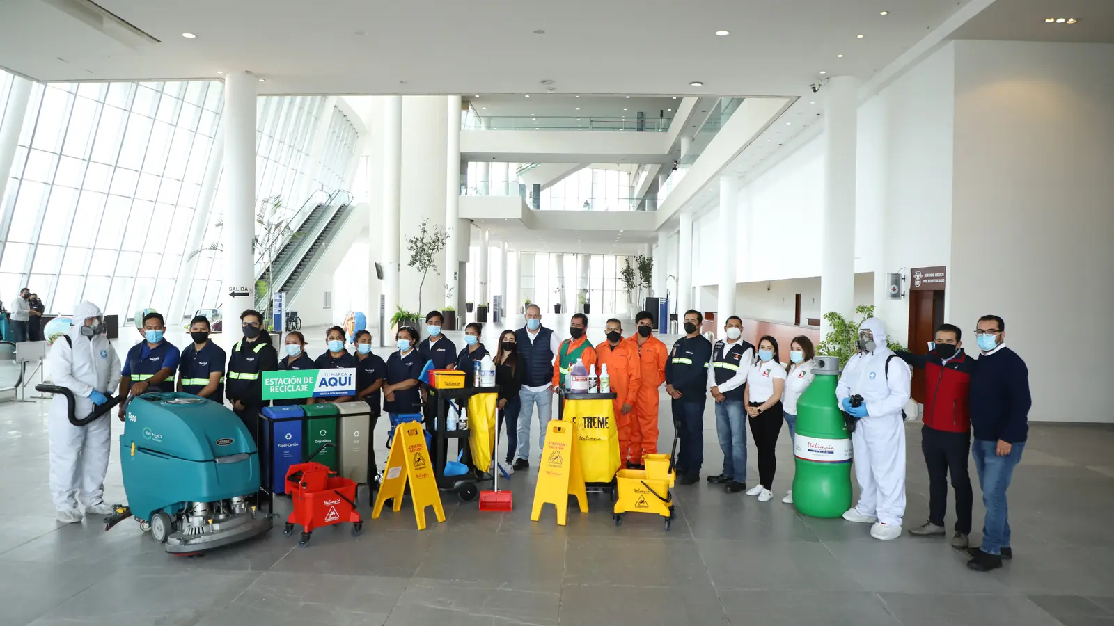 Cuadrilla de Grupo CCN con autolavadora industrial y carros de limpieza completos en el vestíbulo de un corporativo