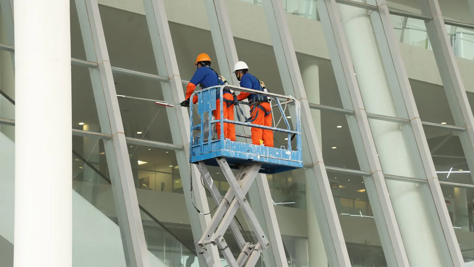 Técnicos de Grupo CCN dando mantenimiento a fachada de cristal desde plataforma elevadora